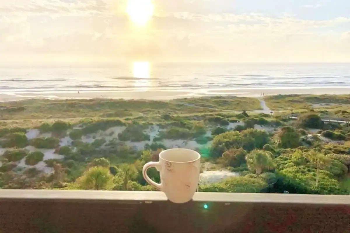 Coffee mug on a balcony overlooking the beach at sunrise