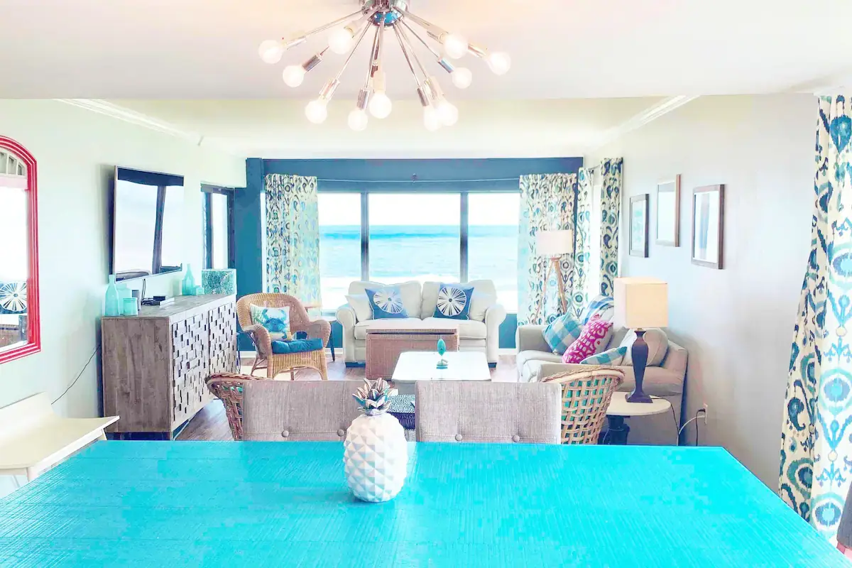 Turquoise dining table and open living area with an ocean view