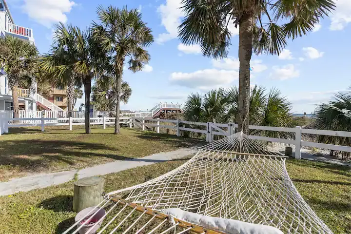 Hammock beneath palm trees beside waterfront vacation homes