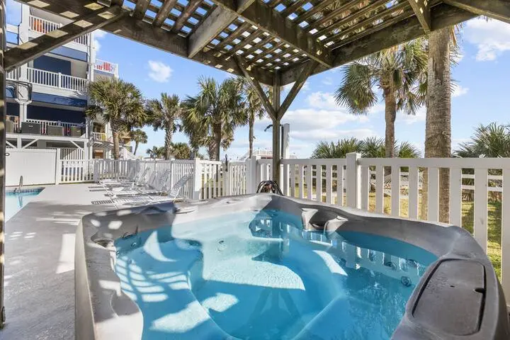 Covered patio with a hot tub overlooking the ocean