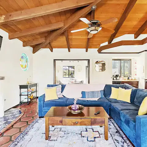 Bright living room with blue sofas and an exposed wood ceiling